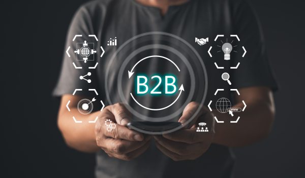 A person holds a smartphone displaying a holographic B2B concept surrounded by icons for collaboration, innovation, growth, and global connectivity, symbolizing modern business to business solutions.